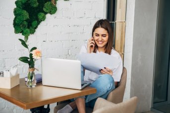 Young Freelancer Girl Talking On The Phone, Holding A Notebook,